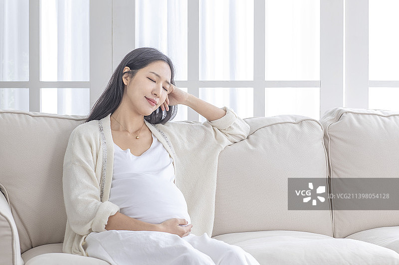 孕妇手摸肚子坐着休息图片素材