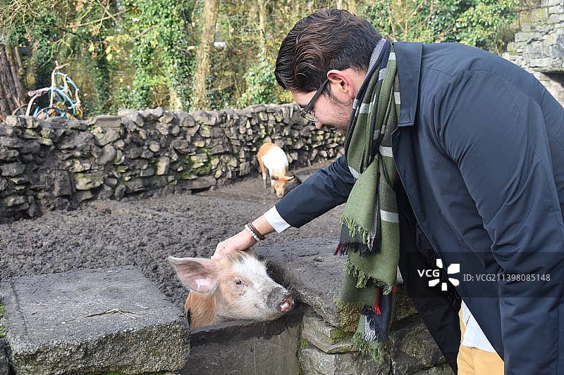 男子在动物园喂鹿的侧面视角图片素材