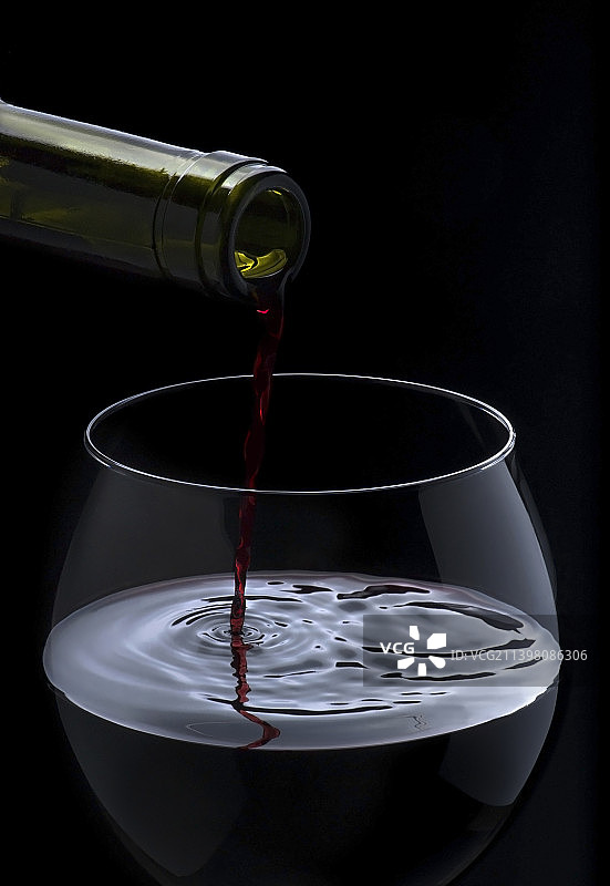 黑色背景下液体倒入瓶中的特写图片素材