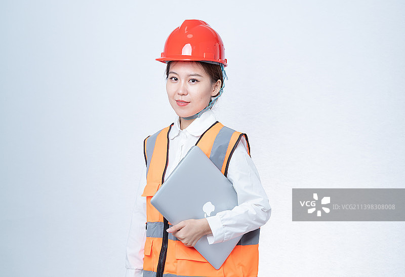 戴着安全帽的女工程师使用笔记本电脑图片素材
