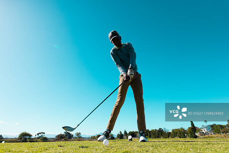 仰视非洲裔青年男子在夏季蓝天下挥杆击球图片素材