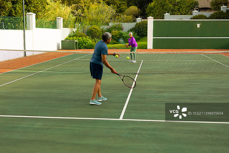 在球场上为年长女子发球的混血年长男子全身照图片素材