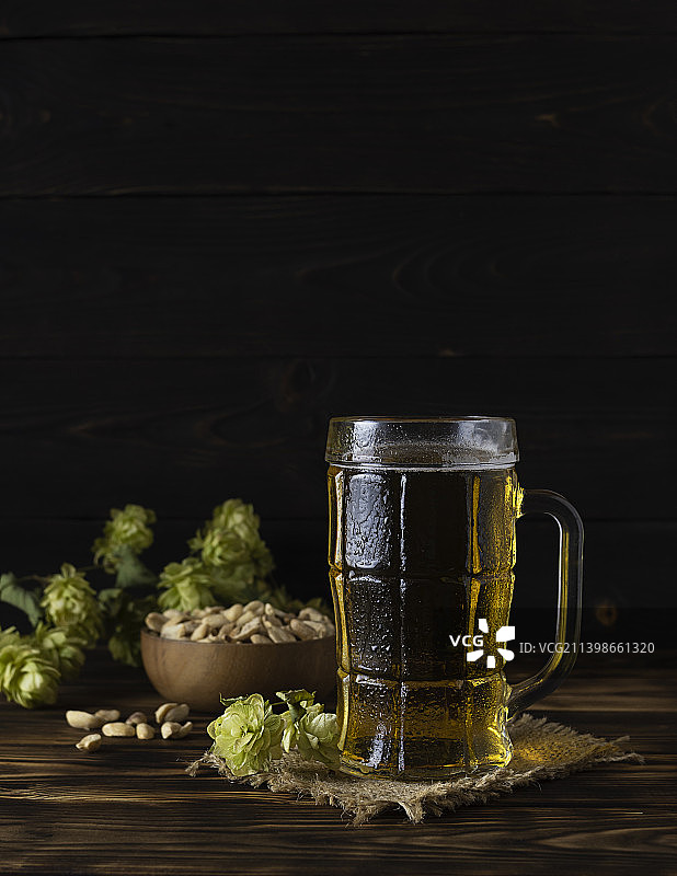 透明马克杯中带泡沫的金色冰镇啤酒在帆布餐巾上图片素材