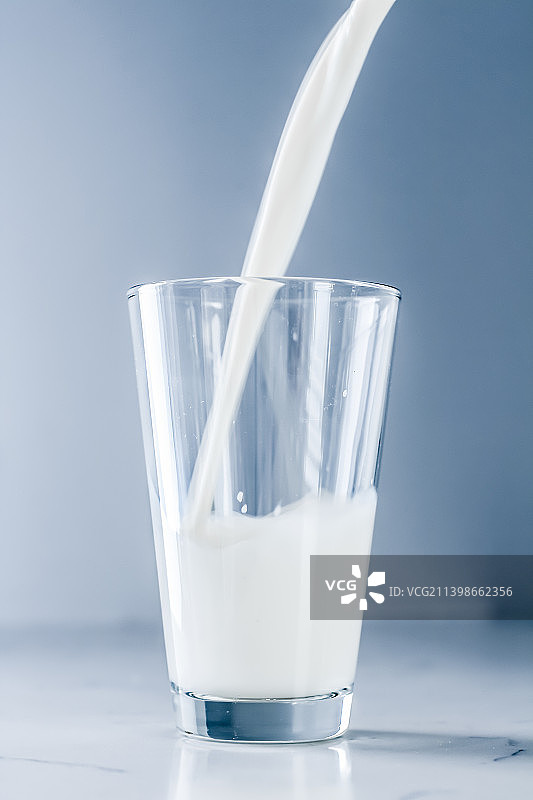 世界牛奶日，将牛奶倒入大理石桌上的玻璃杯中图片素材