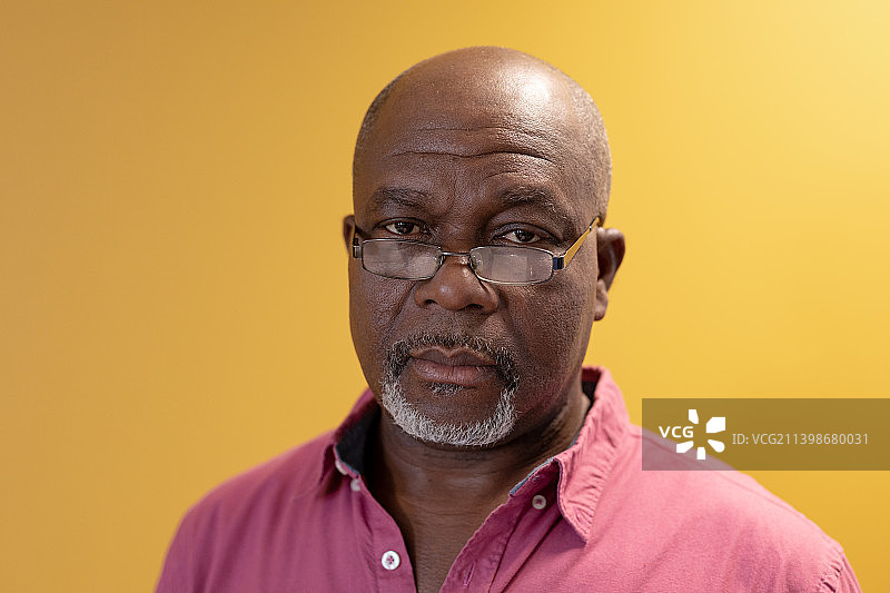 戴眼镜的成熟非裔美国商人肖像，黄色背景图片素材