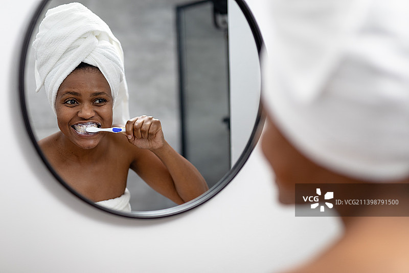 在浴室照镜子刷牙的非裔美国中年妇女图片素材