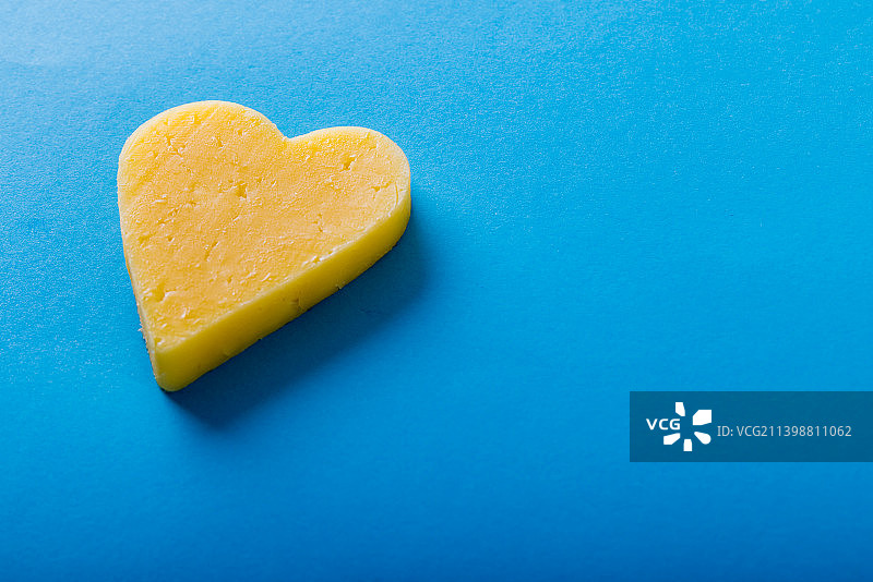 蓝色背景上的心形黄色奶酪高角度视图，带文案空间图片素材