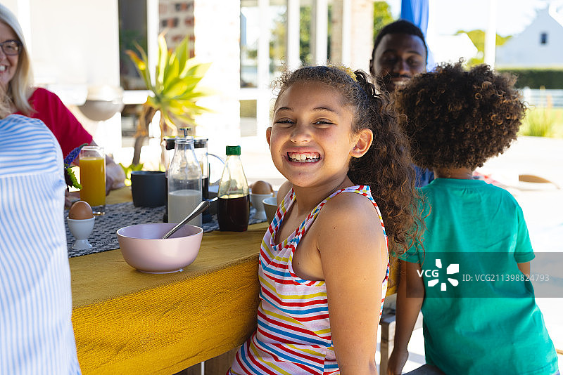微笑的多代可爱女孩在家里的餐桌上与家人共进早餐的肖像图片素材