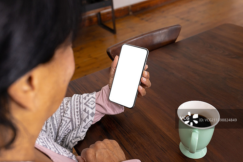 在家喝咖啡玩手机的混血中年妇女俯视图图片素材