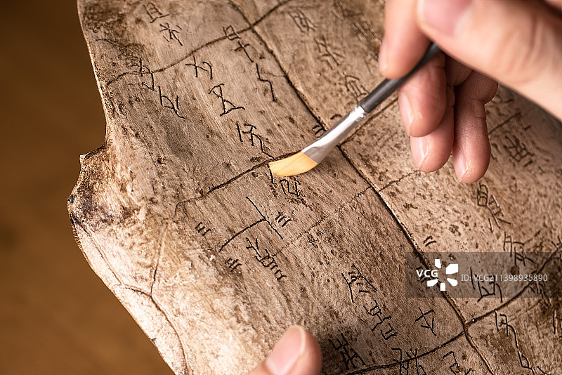 考古人员手拿刷子清除文物上甲骨文上沙土图片素材