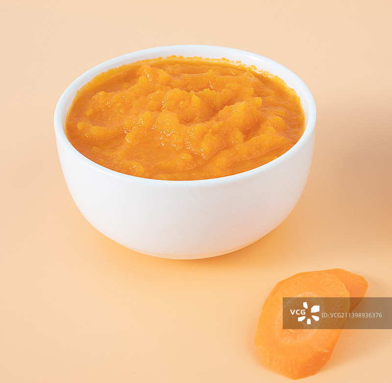 橙色背景中一碗婴儿辅食胡萝卜泥图片素材