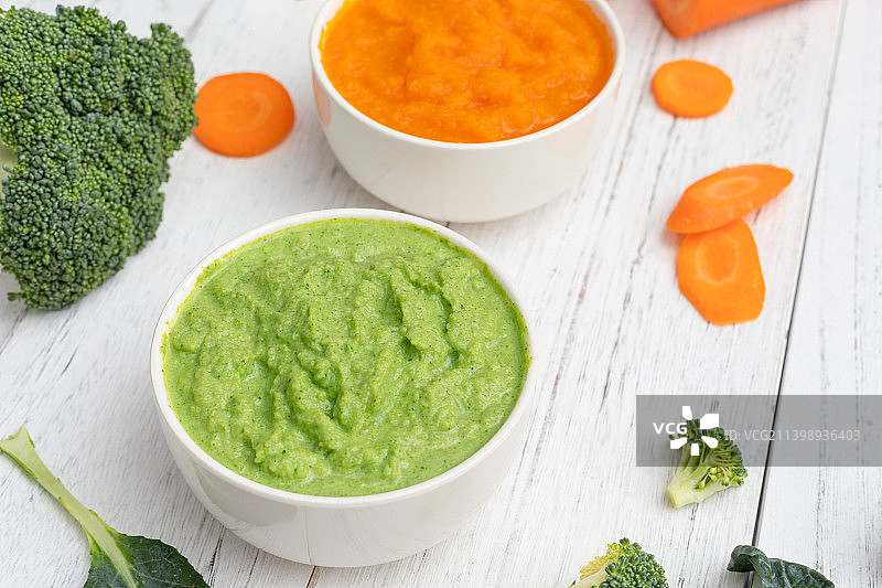 白色木纹背景中的婴儿辅食西兰花泥和胡萝卜泥图片素材