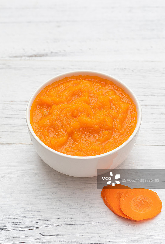 白色木纹背景中一碗婴儿辅食胡萝卜泥图片素材