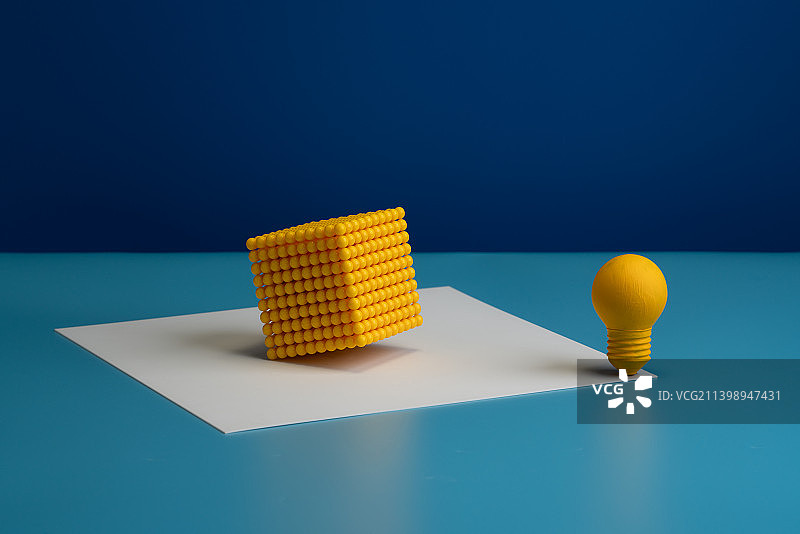 放在蓝色背景中的黄色灯泡和黄色塑料块静物图图片素材