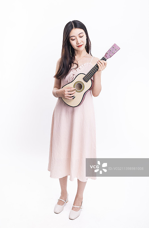 穿着粉色连衣裙拿着尤克里里的女孩图片素材