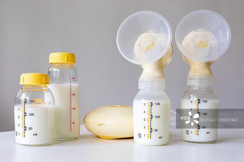 桌面上的吸奶器和装满了母乳的奶瓶图片素材