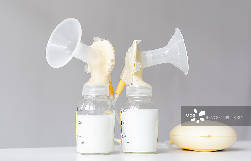 桌面上的吸奶器和装满了母乳的奶瓶图片素材