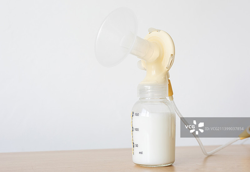 桌面上的吸奶器和装满了母乳的奶瓶图片素材
