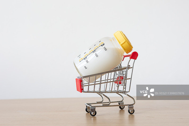 桌面上一个奶瓶放在购物车模型上图片素材