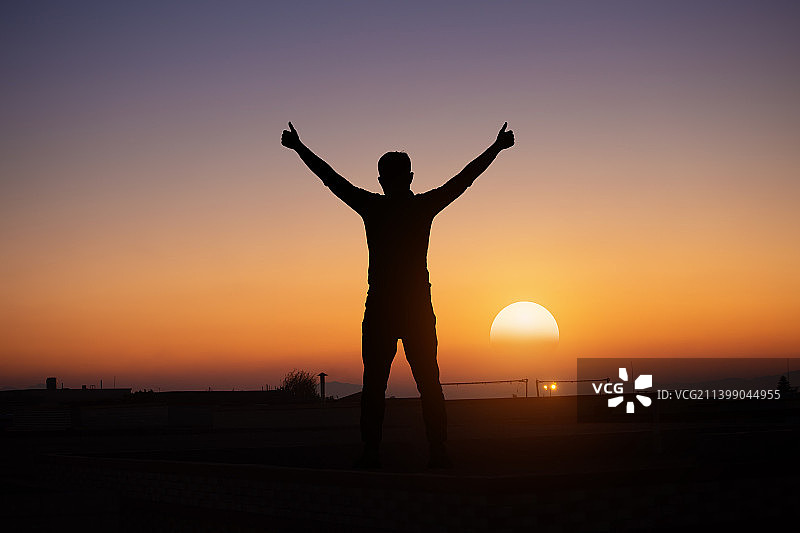 一男性身影拥抱东方日出的朝霞图片素材