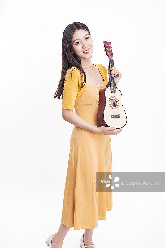 穿着黄色连衣裙拿着尤克里里的女孩图片素材