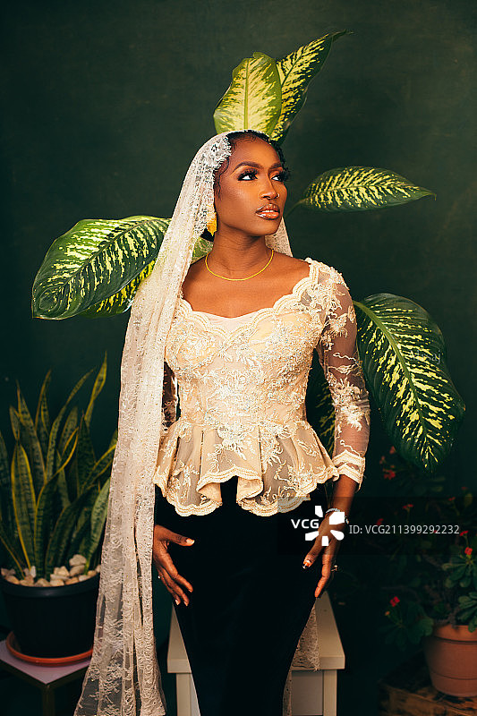 在盆栽绿色植物前的年轻女子，阿布贾，尼日利亚图片素材