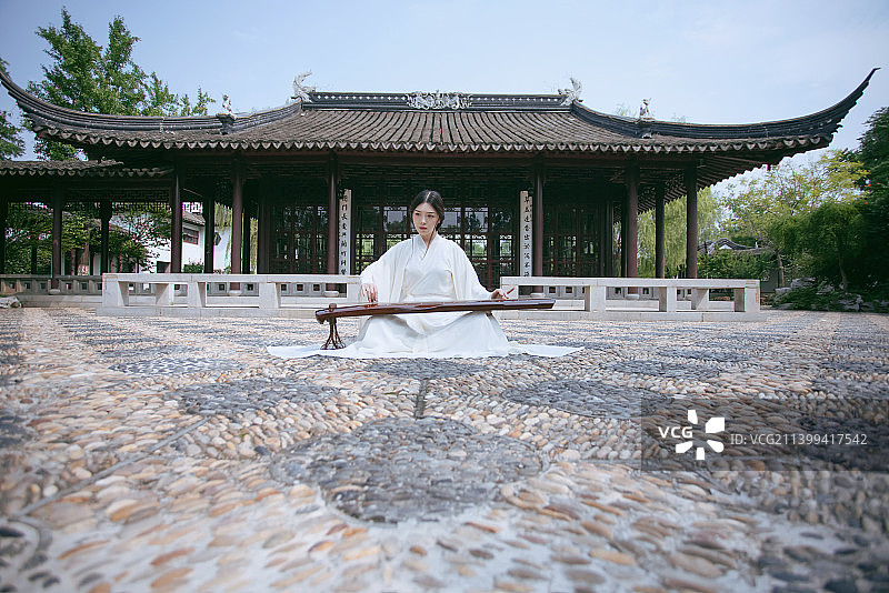 一个汉服美女坐在中式大殿前弹古琴图片素材