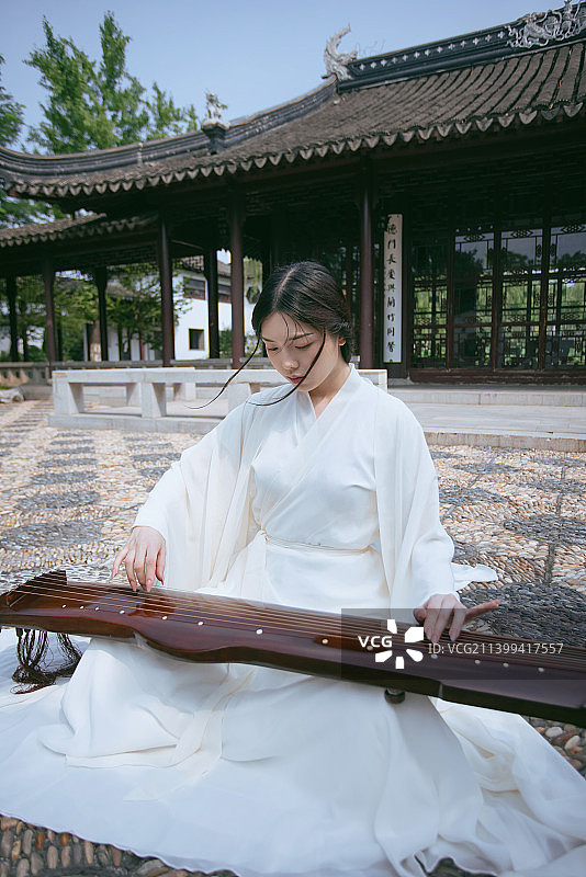 一个汉服美女坐在中式大殿前弹古琴图片素材
