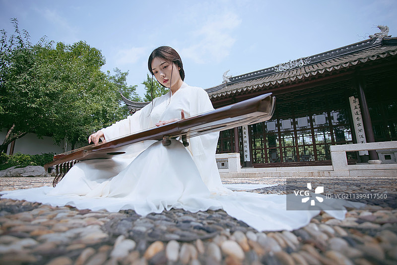 一个汉服美女坐在中式庭院中弹古琴图片素材