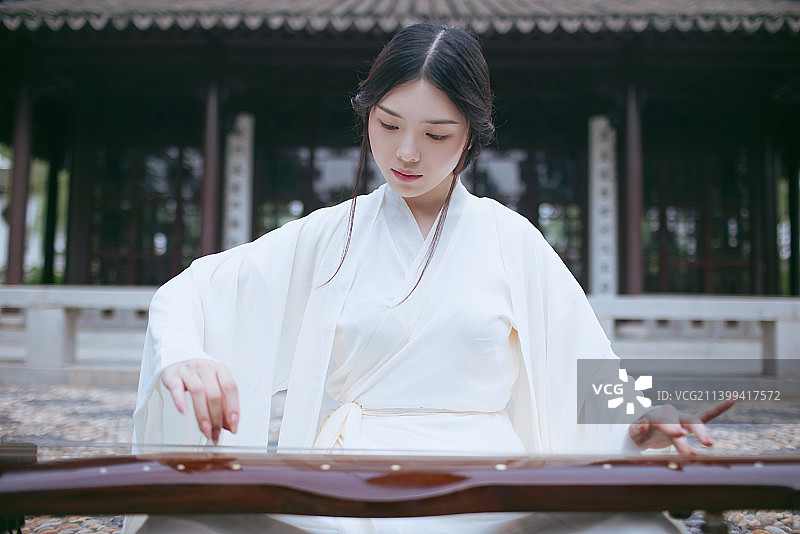 一个汉服美女坐在中式庭院中弹古琴特写图片素材