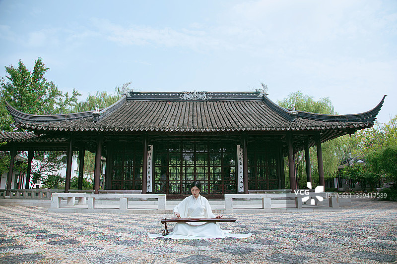 一个汉服美女坐在苏式园林中弹古琴图片素材