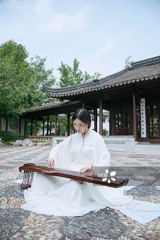一个汉服美女坐在苏式园林中弹古琴图片素材