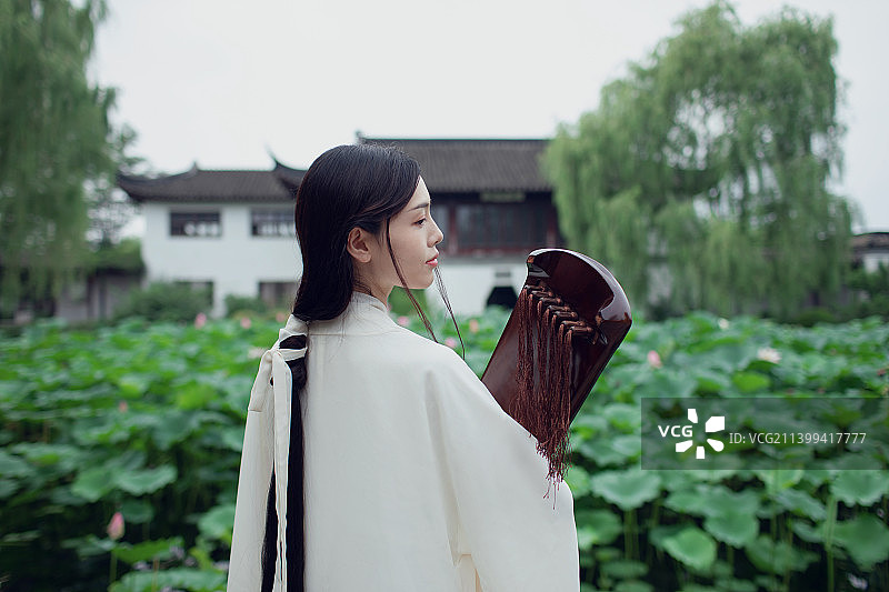 古装长发美女抱着古琴站在荷塘边图片素材