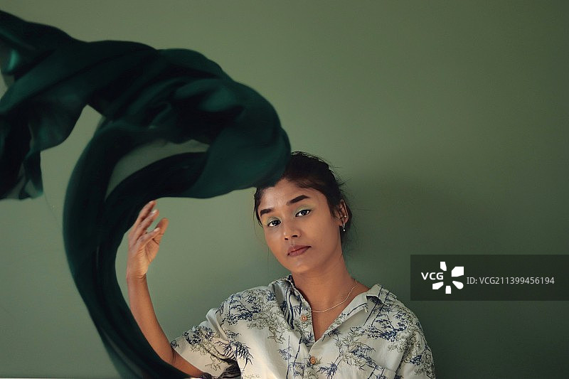 在墙边挥舞绿色围巾的女人图片素材