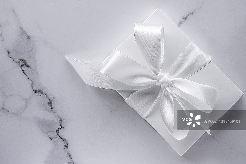 大理石背景上带丝绸蝴蝶结和丝带的豪华结婚礼物图片素材