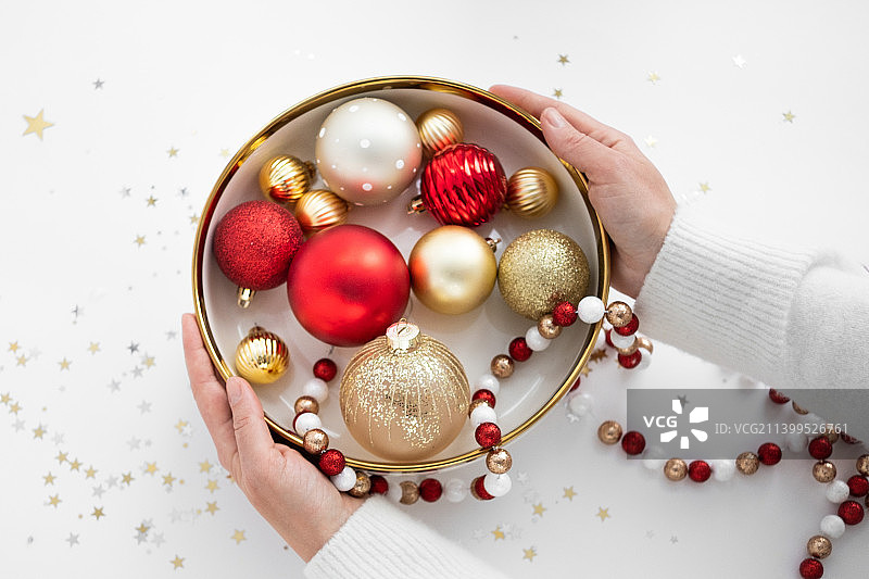 手持新年装饰（金色和红色）及彩纸的人图片素材