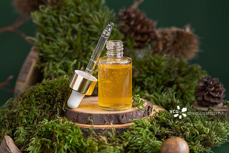 打开的滴管瓶与绿色苔藓中的黄色液体，特写天然化妆品图片素材