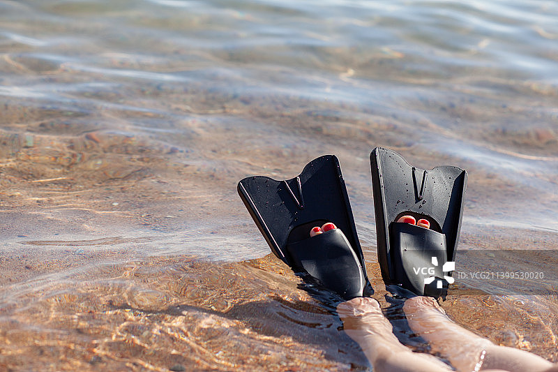 穿着黑色脚蹼的女人在岸边附近溅水，脚蹼伸出图片素材