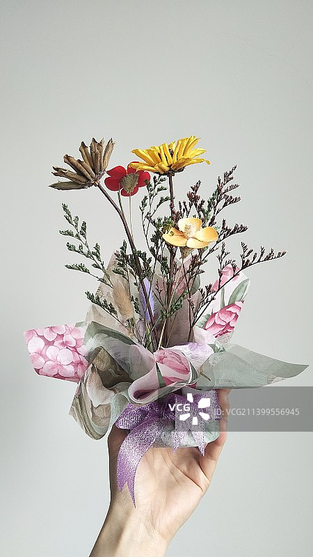 白色背景下手持花束的特写镜头图片素材