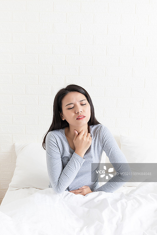 卧室里一名喉咙痛的年轻女性图片素材