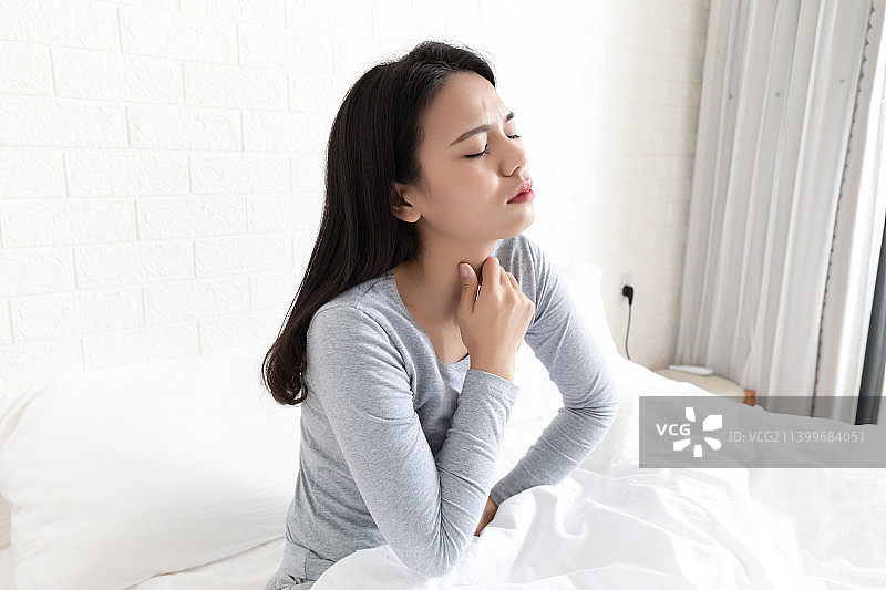 卧室里一名喉咙痛的年轻女性图片素材
