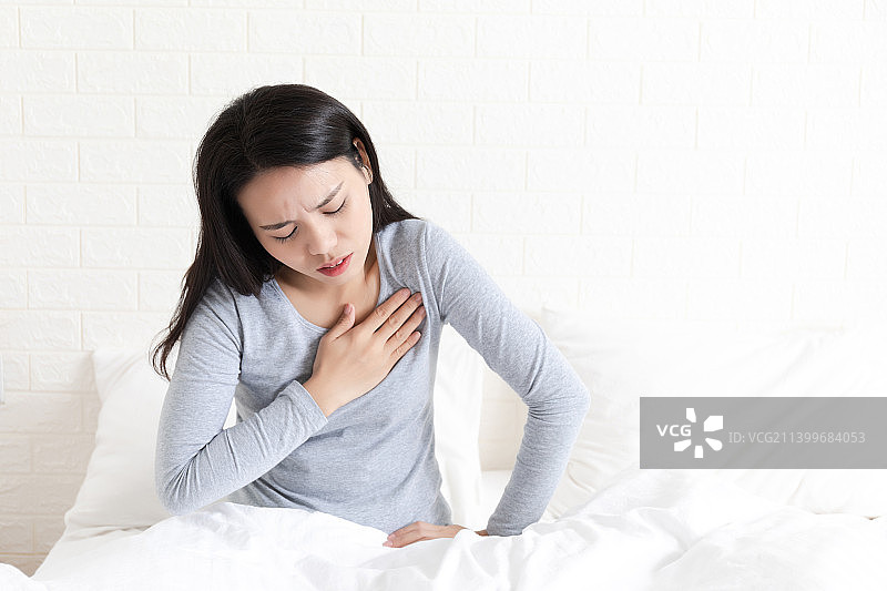 卧室里一名胸痛的年轻女性图片素材