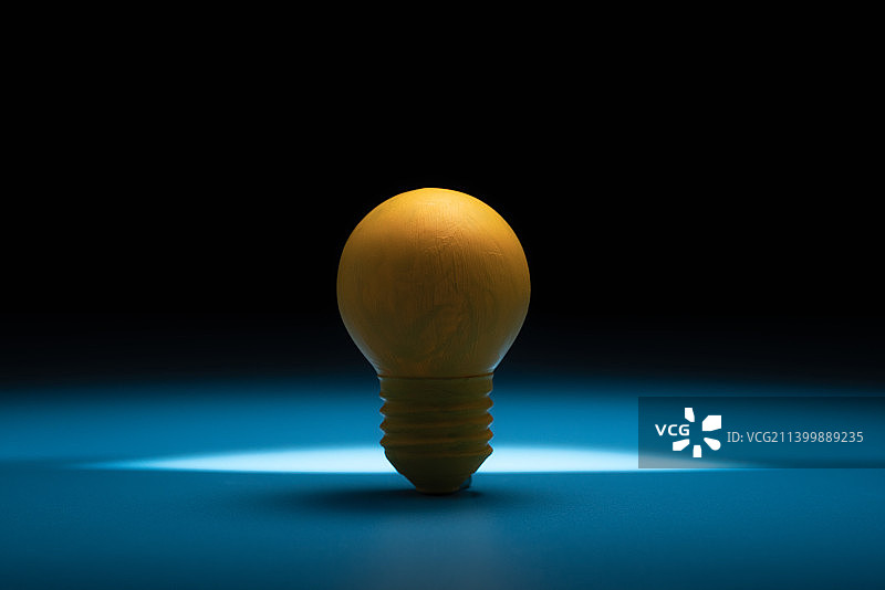 一个黄色灯泡放在暗调的背景中静物图图片素材