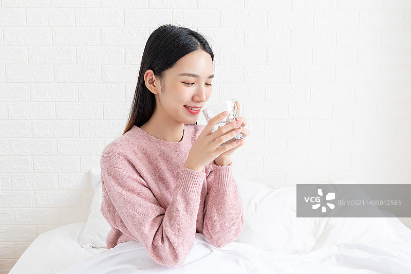 卧室里一名年轻女性在喝水图片素材