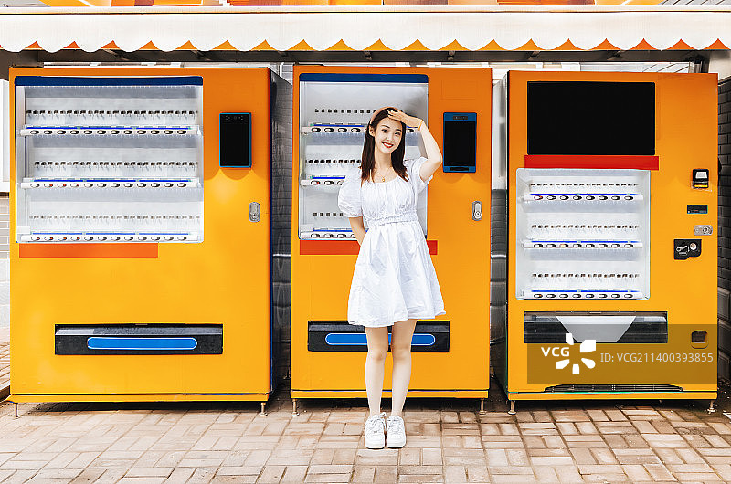自动售货机旁的美丽东方女性图片素材