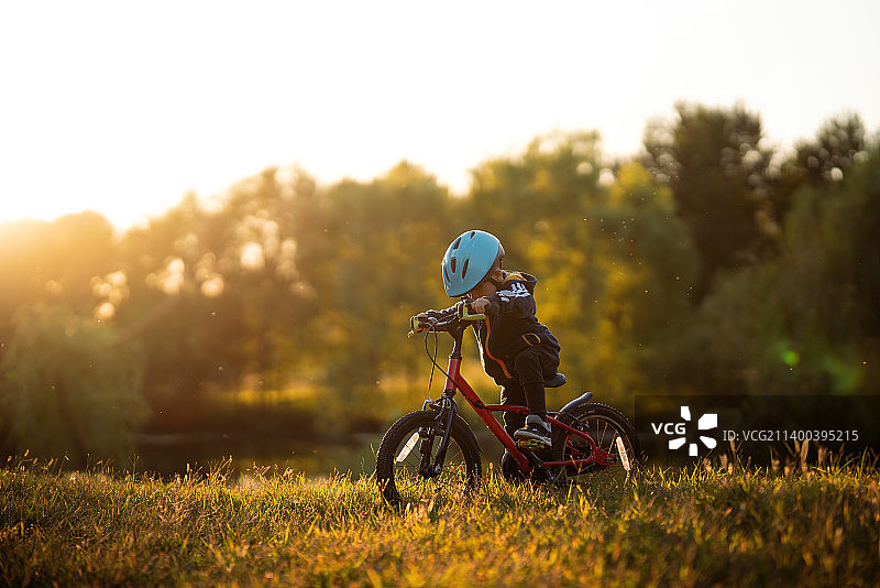 哥哥和弟弟俩人在夕阳下的树林里骑自行车图片素材