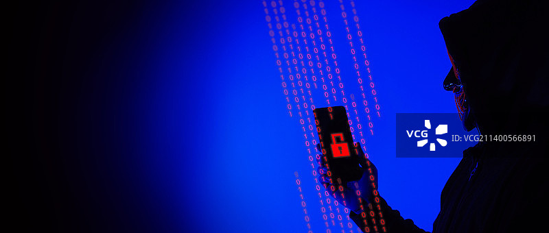 数字安全概念：匿名黑客戴着面具，手持智能手机入侵个人和网络图片素材