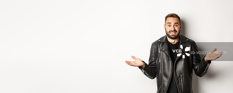 困惑的络腮胡男人穿着黑色皮夹克寻求建议图片素材