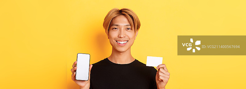 展示智能手机屏幕的微笑亚洲男子特写图片素材