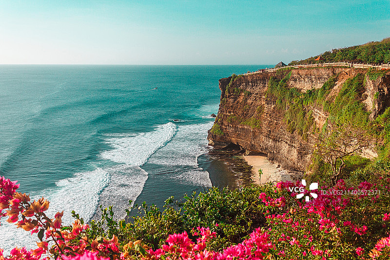 印度尼西亚巴厘岛乌鲁瓦图悬崖附近的海洋波浪，海上的日落，岩石和花朵图片素材